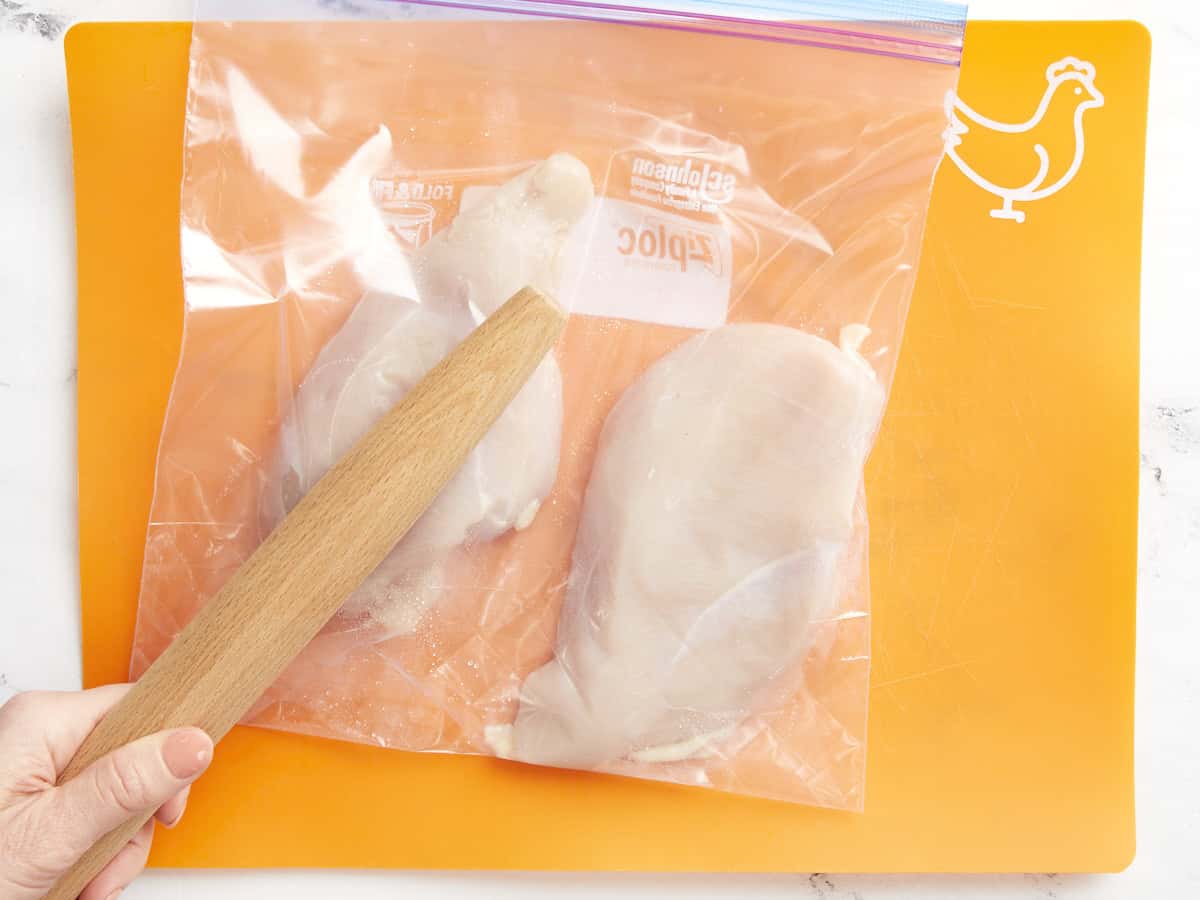 Pounding chicken breasts in a Ziplock bag with a rolling pin.