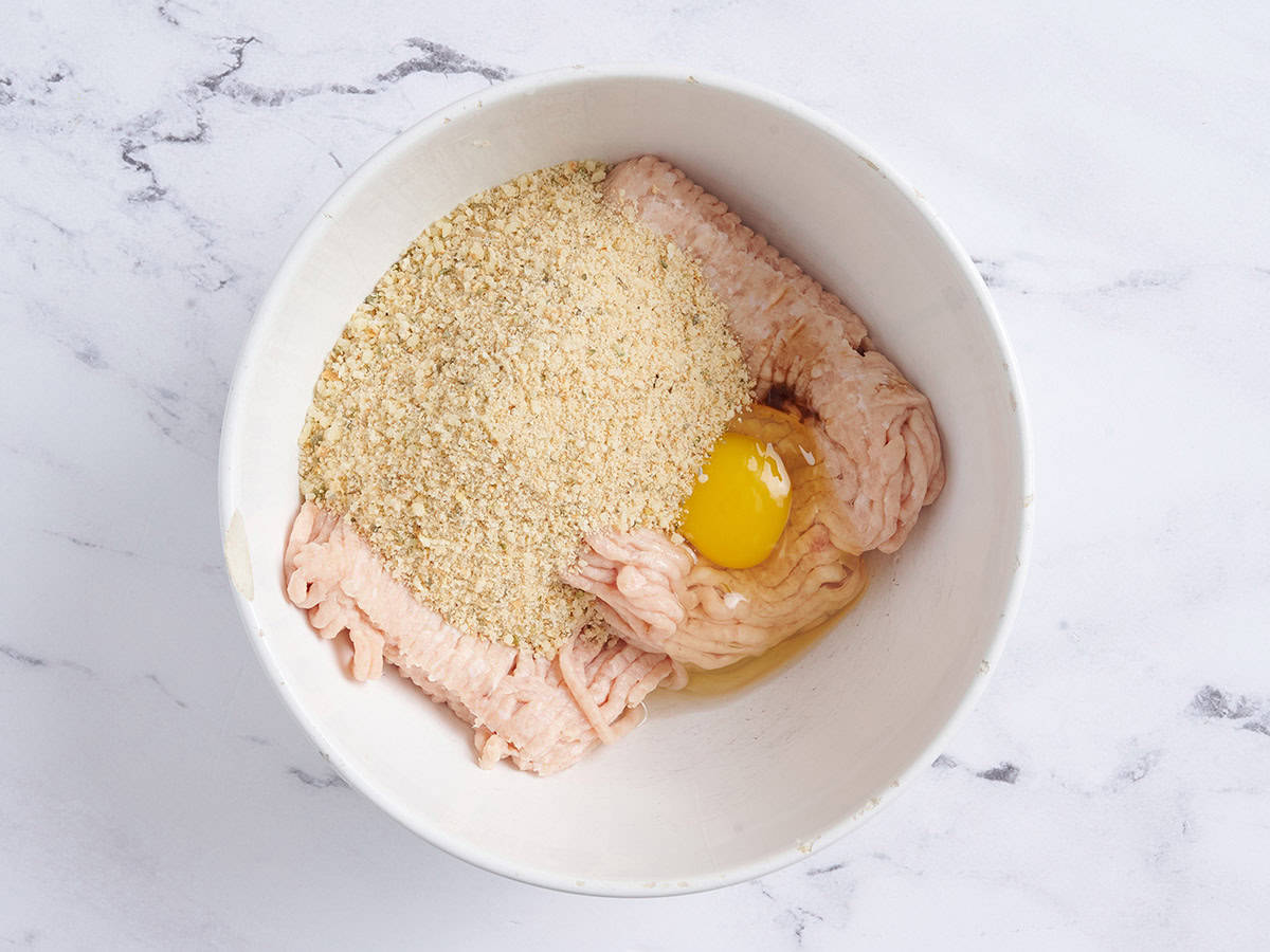 Ground chicken, egg, and breadcrumbs in a bowl.