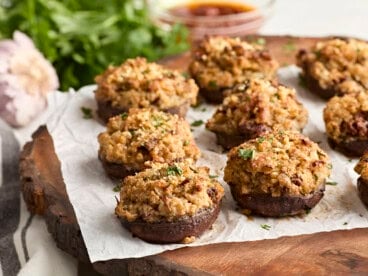 Side view of stuffed mushrooms on a wooden chopping board.
