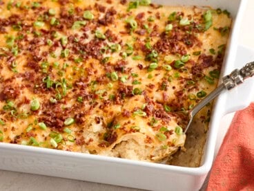 Side view of a spoon taking mashed potato casserole from a baking dish.