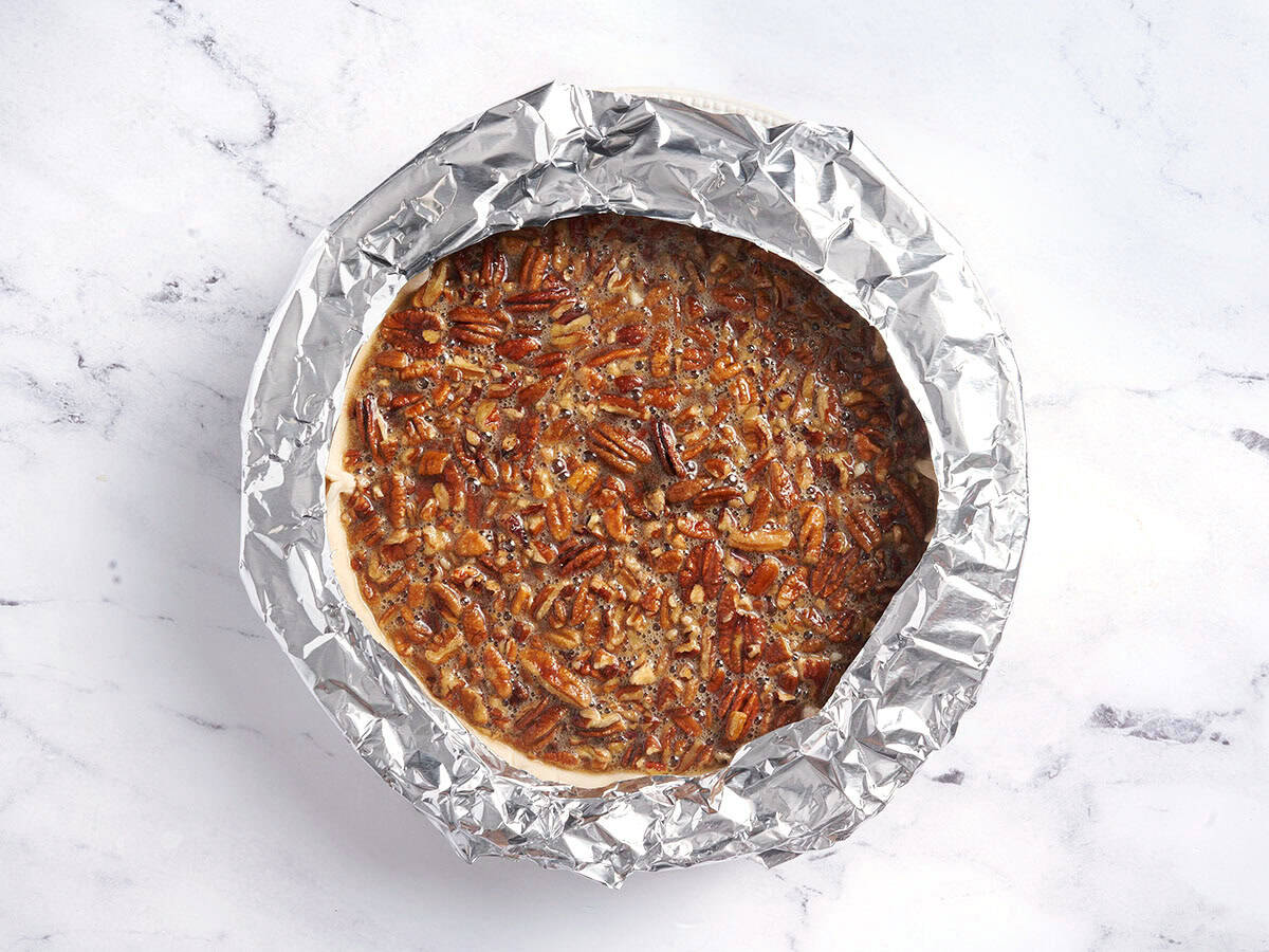 A foil tent added to a pecan pie.