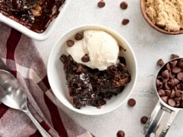 Overhead view of a slice of chocolate pudding cake in a bowl with vanilla ice cream.