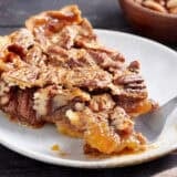 Side view of a slice of pecan pie with a fork taking some.