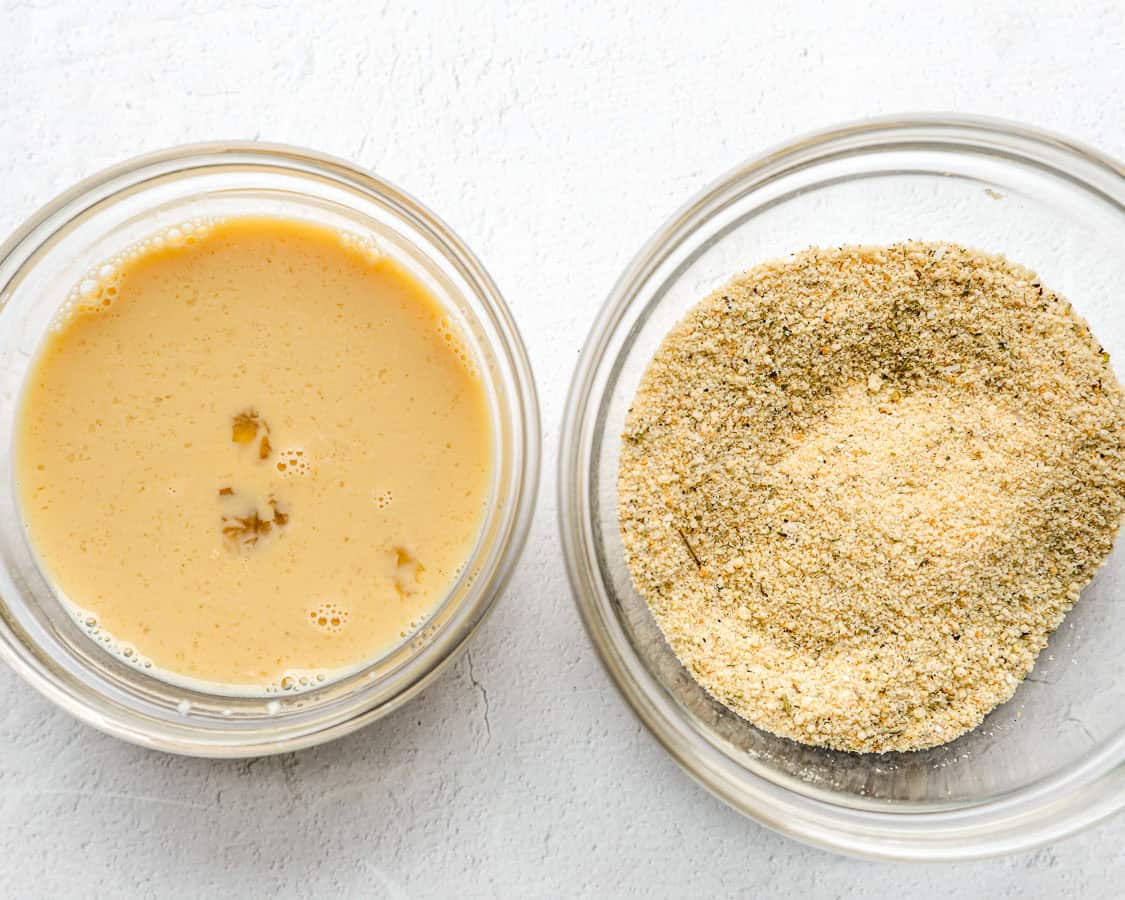 Seasoned breadcrumbs in a bowl and whisked egg and milk in another bowl.