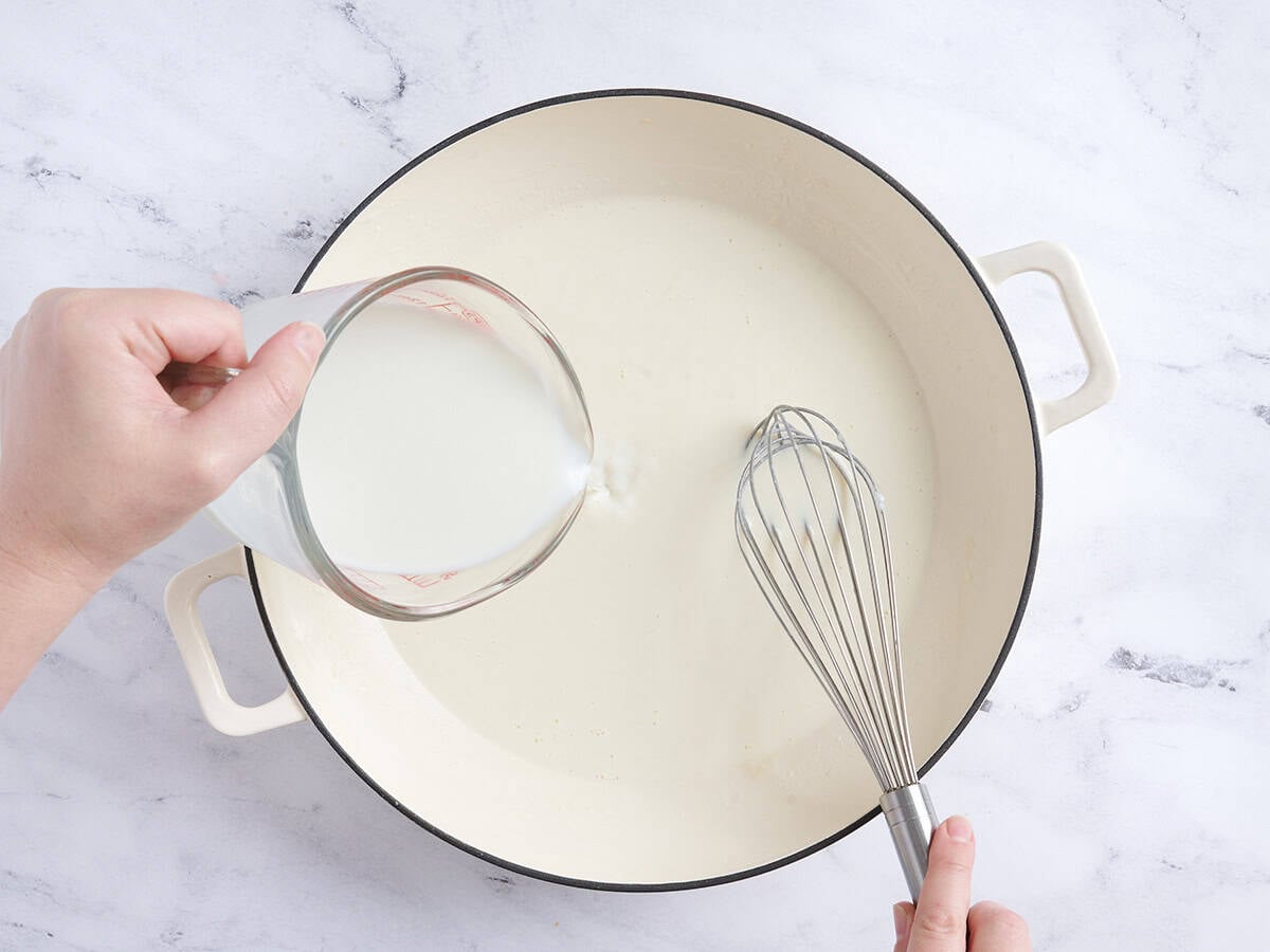 Milk being poured and whisked into a skillet.