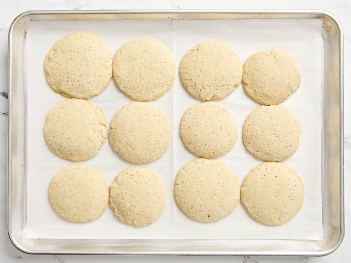 Baked eggnog cookies on a parchment lined baking sheet.