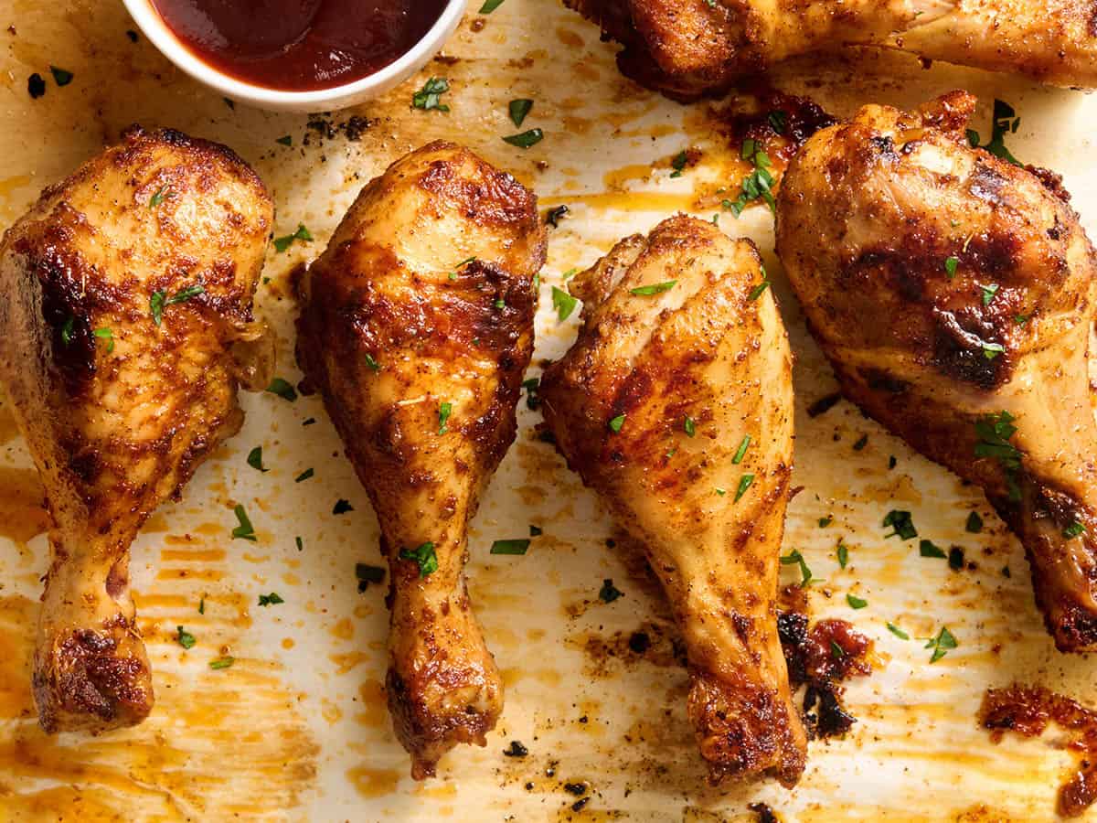 Overhead view of baked chicken drumsticks on a baking sheet.