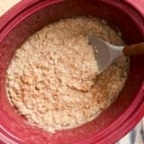 Overhead view of slow cooker steel cut oats in a crockpot with a spoon.