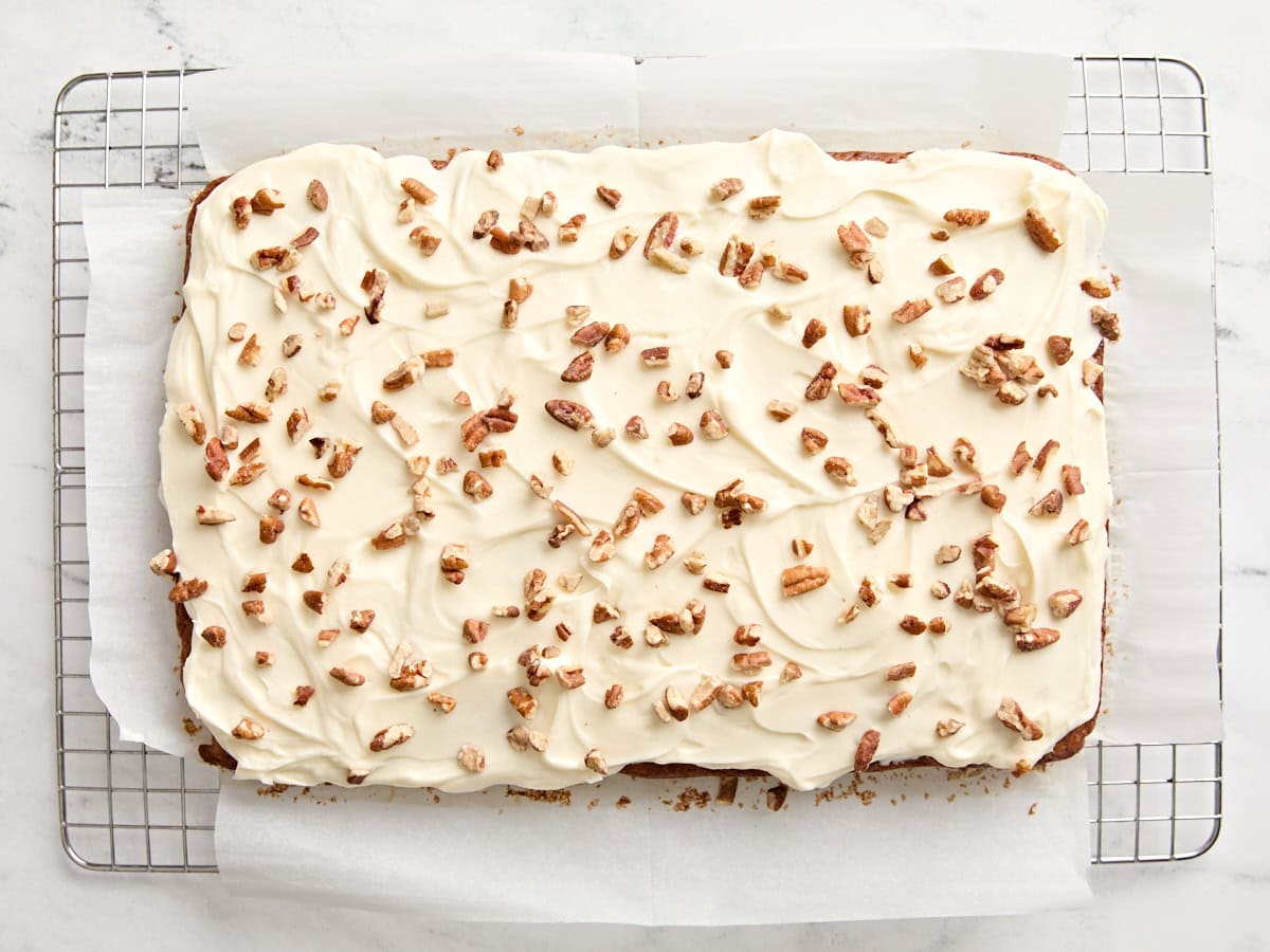 Finished carrot cake topped with a cream cheese frosting and chopped walnuts.