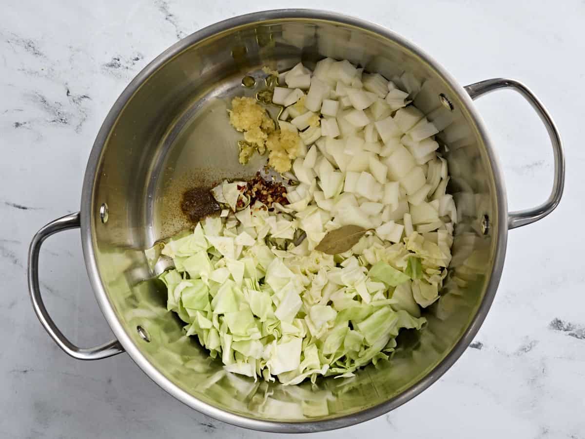 Diced onion, cabbage, minced garlic, and seasonings in a soup pot.