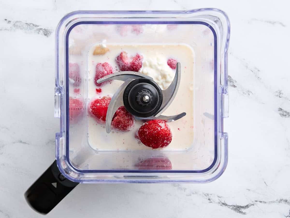 Frozen banana, frozen strawberries, cottage cheese, milk, and vanilla extract in a blender.