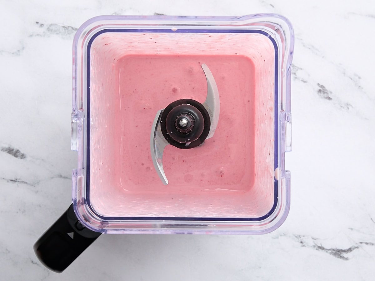Overhead view of a strawberry cheesecake smoothie in a blender.