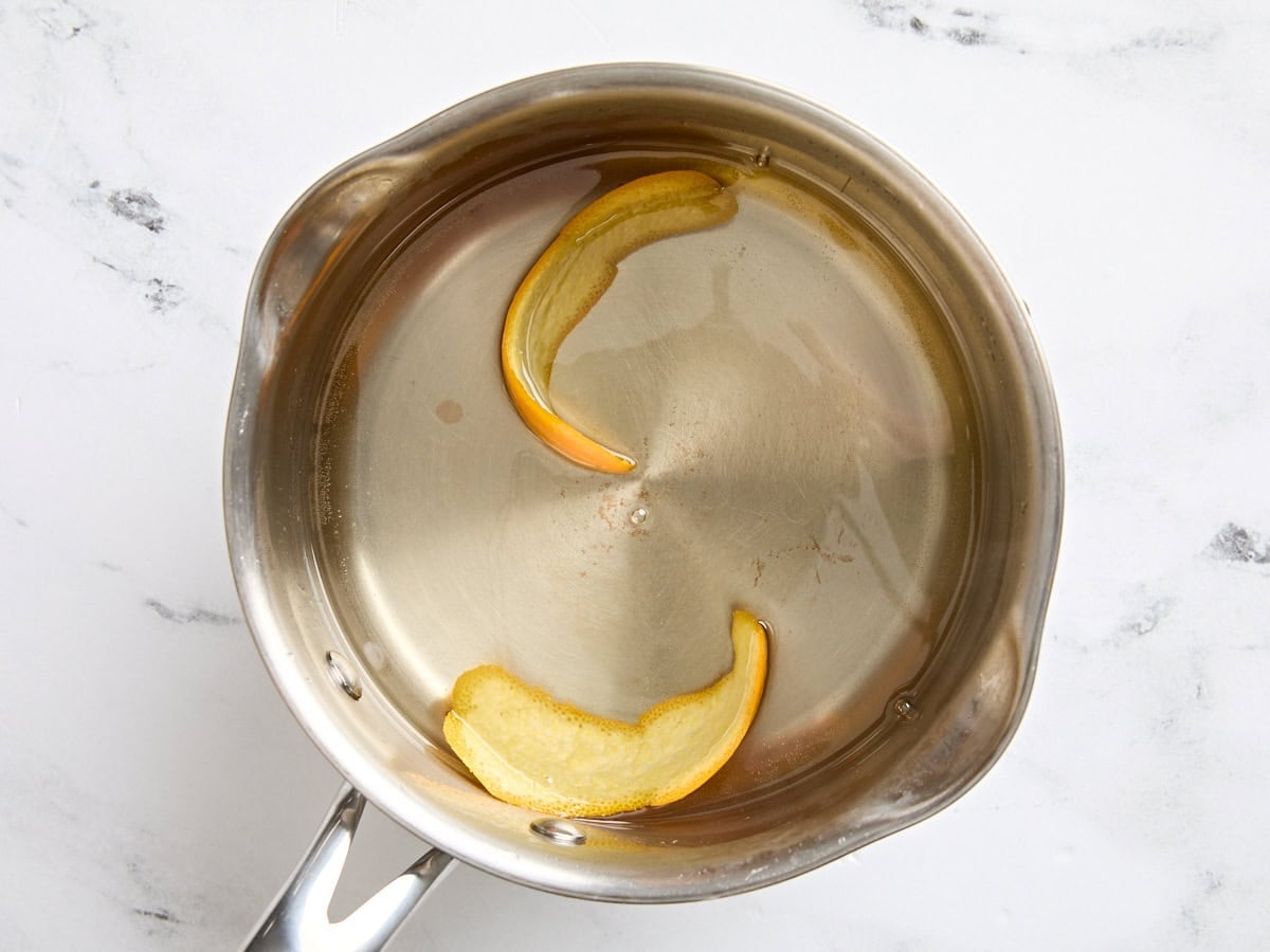 Simple syrup in a pot with orange peel after cooling.