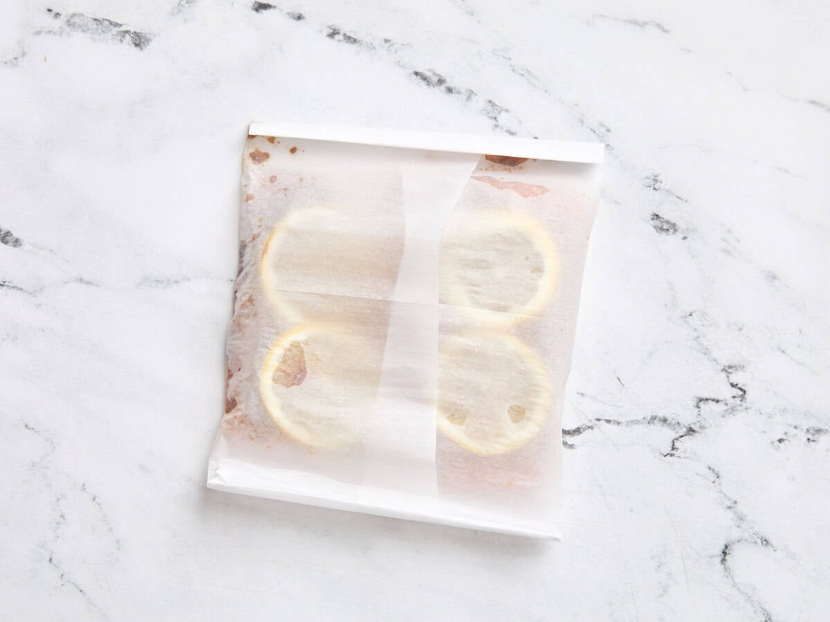 Glazed salmon filets wrapped in a parchment paper parcel for baking.