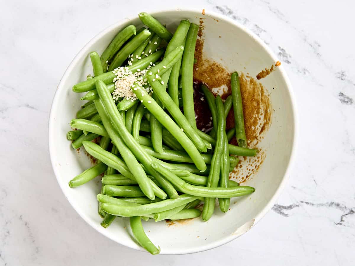 Green beans added to the bowl of sesame oil glaze.