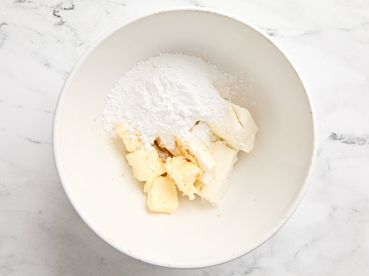 Cream cheese, butter, and powdered sugar in a mixing bowl.