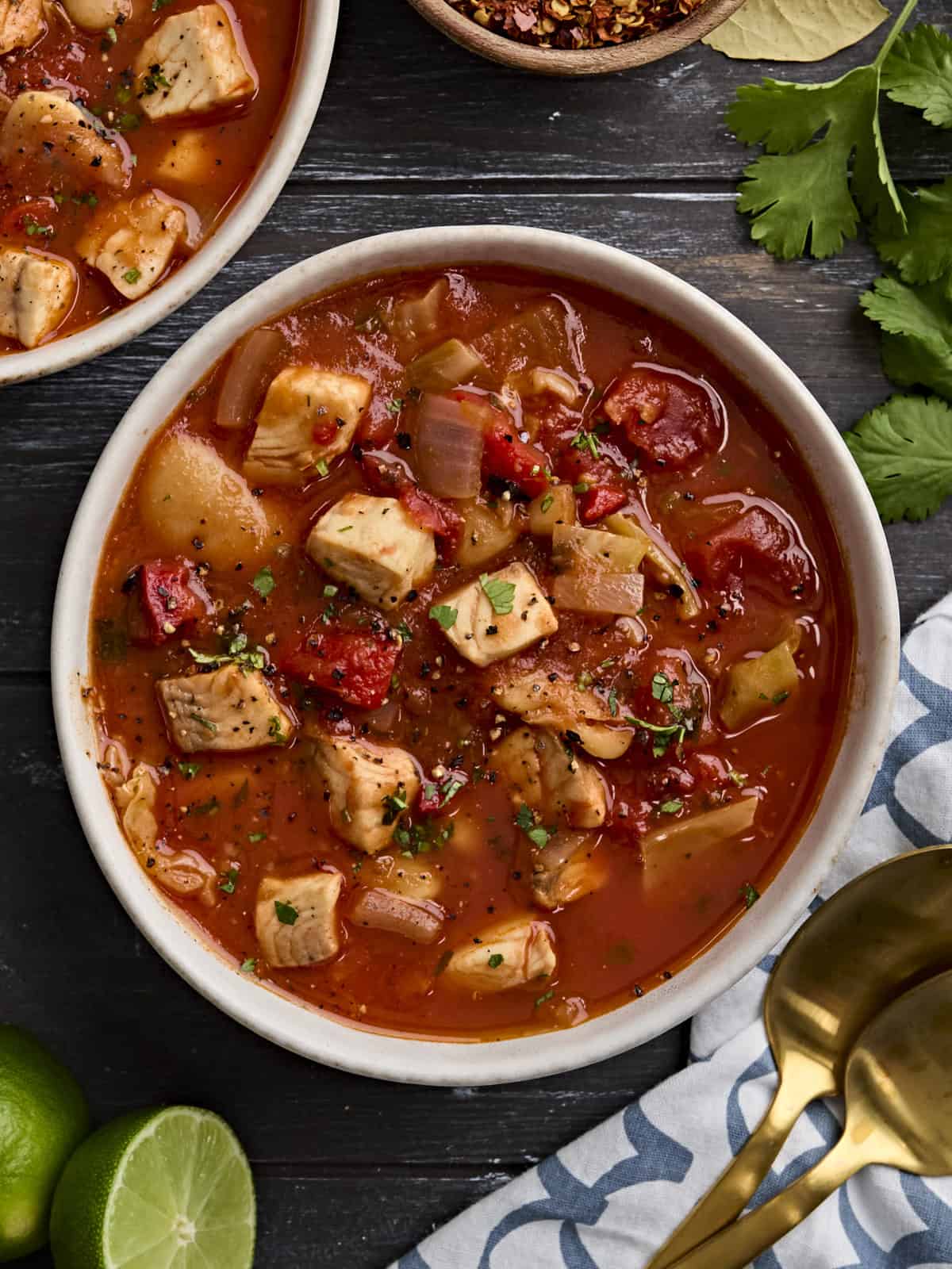 Overhead view of a bowl of fish soup, sprinkled with fresh parsley.