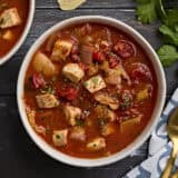 Overhead view of a bowl of fish soup, sprinkled with fresh parsley.