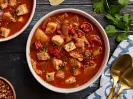Overhead view of a bowl of fish soup, sprinkled with fresh parsley.