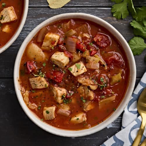 Overhead view of a bowl of fish soup, sprinkled with fresh parsley.