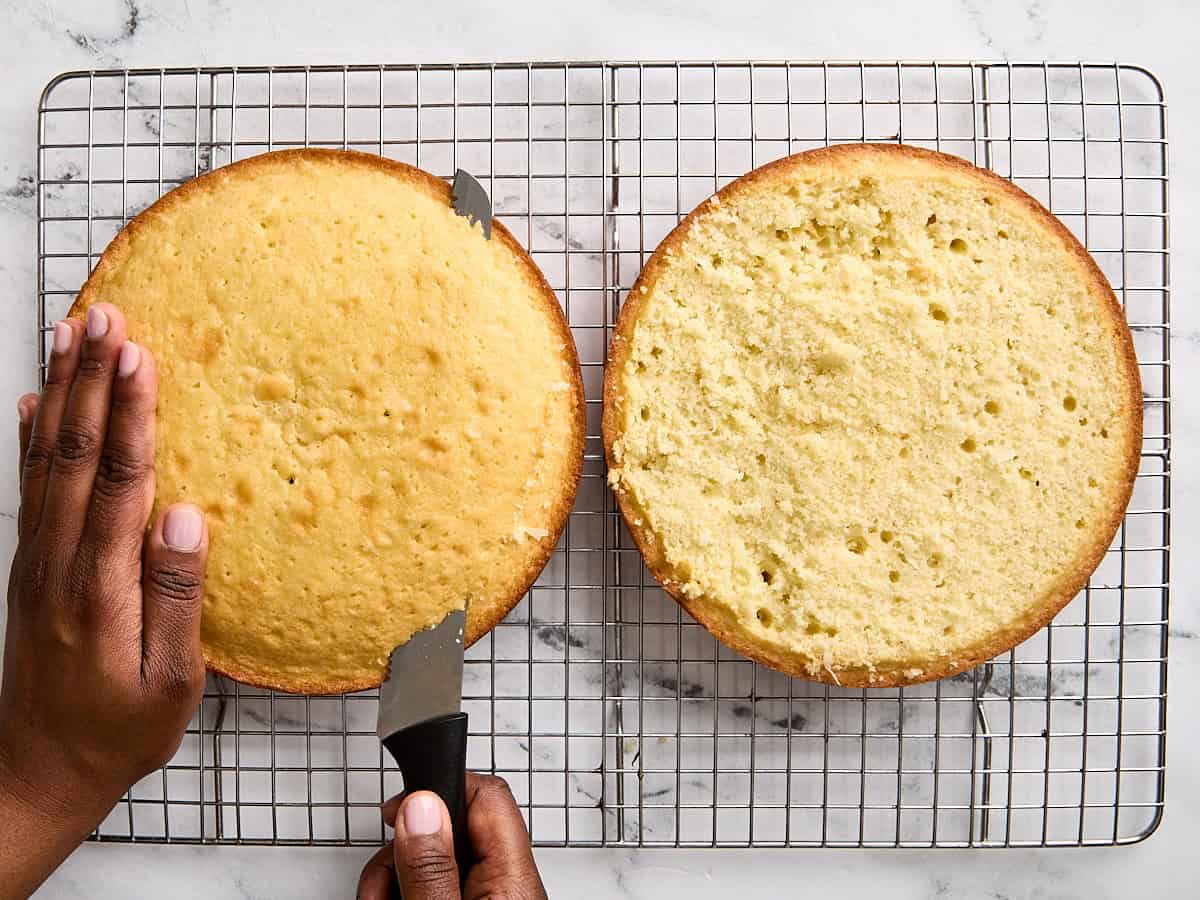 The domed cake tops being cut off two homemade coconut cakes.