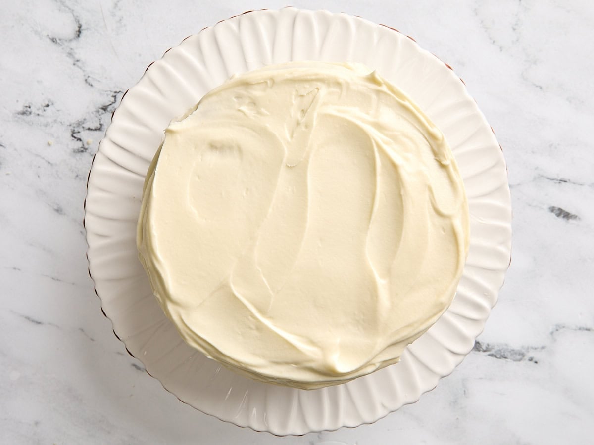 An overhead view of a fully frosted coconut cake.