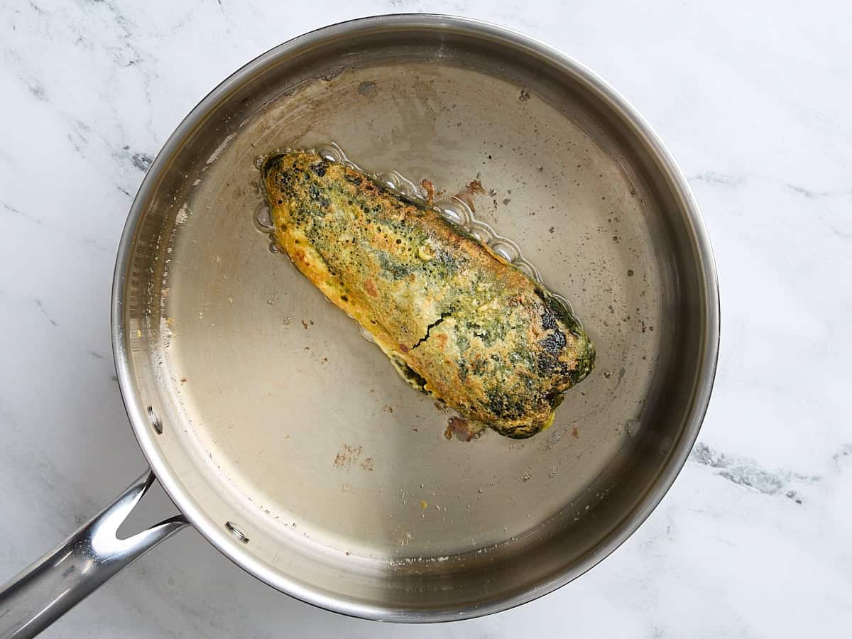 A chile relleno frying in a skillet.