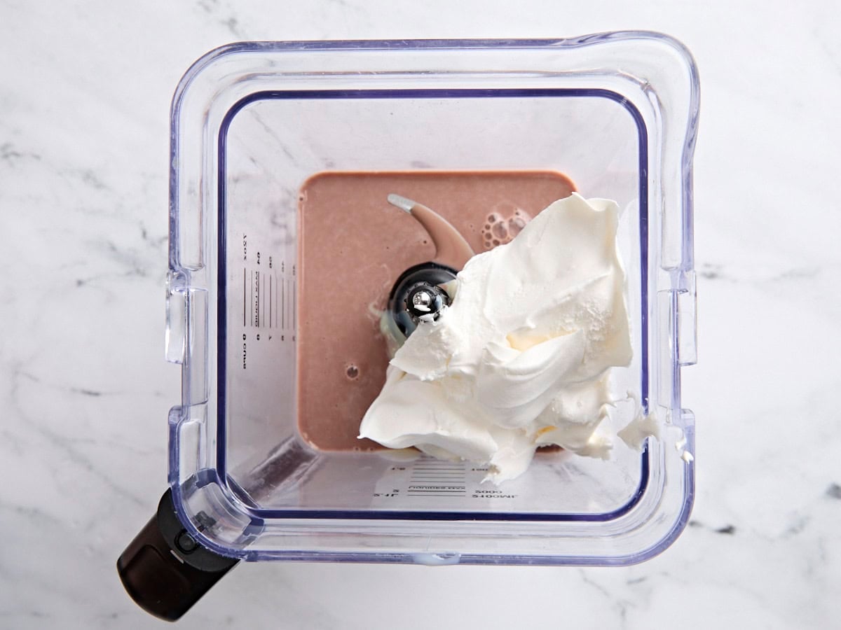 Chocolate milk, cool whip, and sweetened condensed milk in a blender after being blended together.
