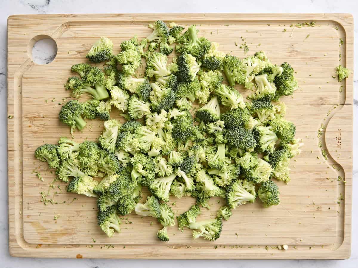 Fresh broccoli florets on a wooden cutting board.