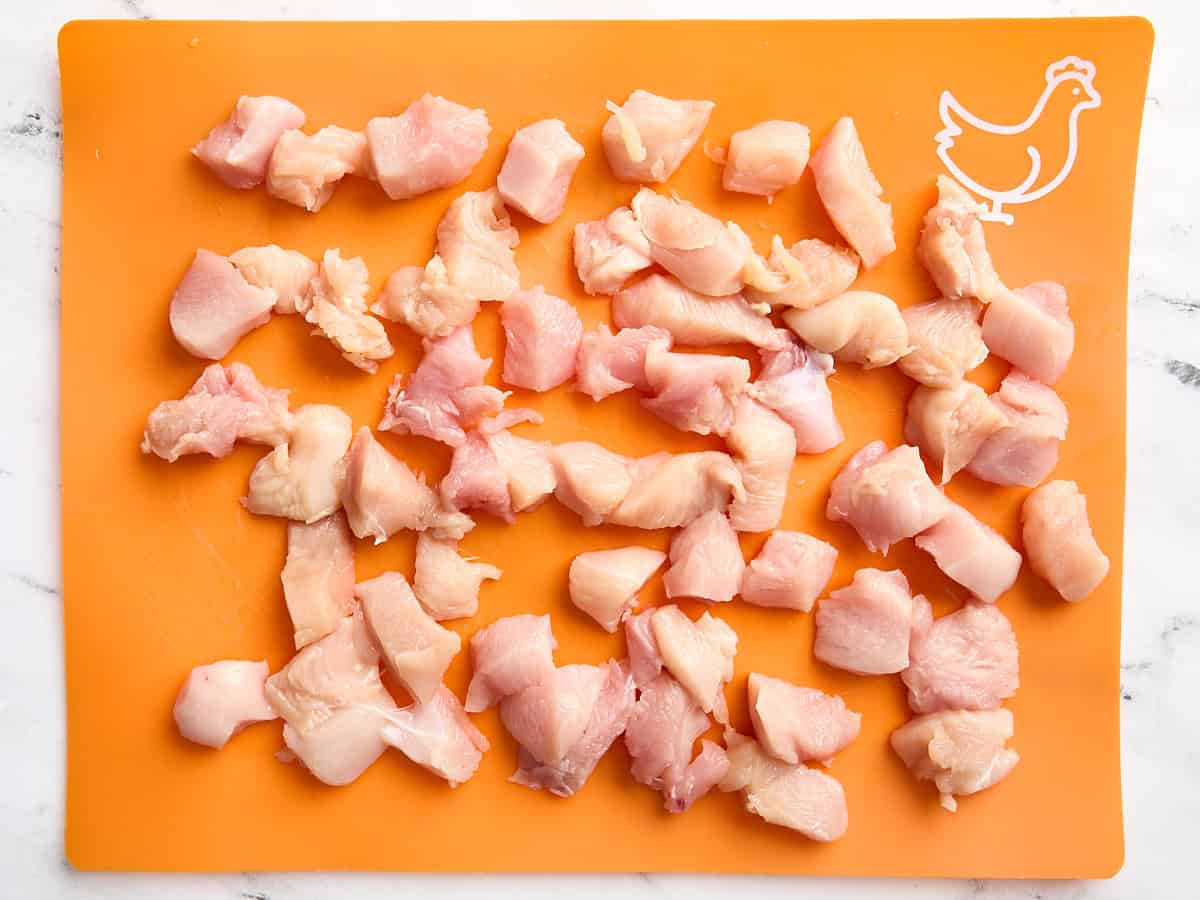 Diced chicken breast on a meat preparation mat.