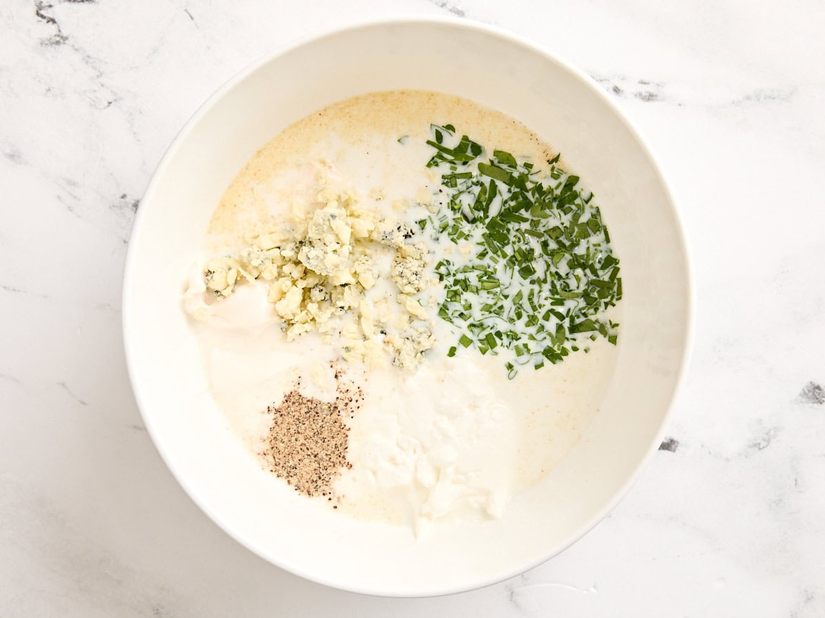 The ingredients for blue cheese dressing in a mixing bowl.