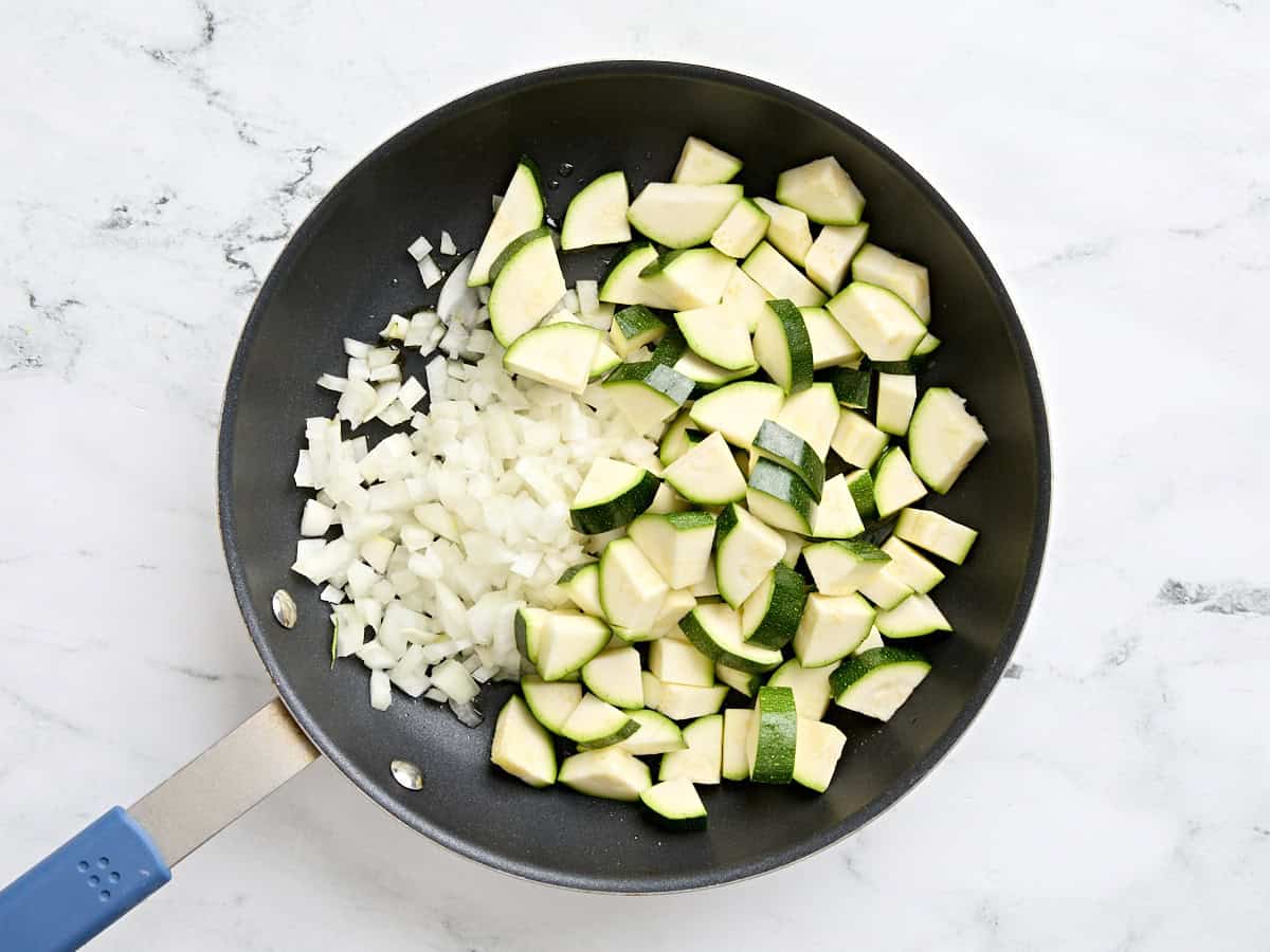 Diced onion and sliced zucchini in a skillet.