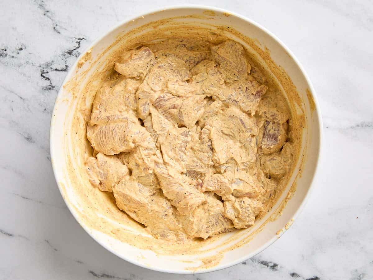 Diced chicken breast marinating in a bowl of butter chicken marinade.