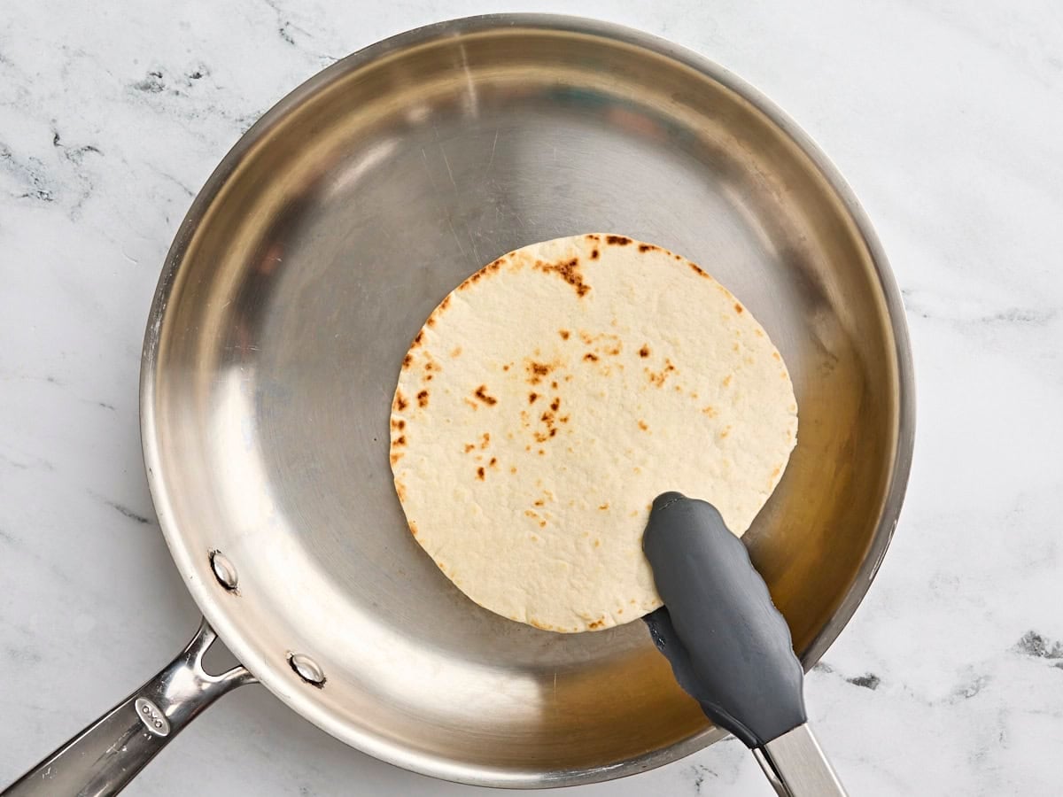 A tortilla being toasted in a skillet.