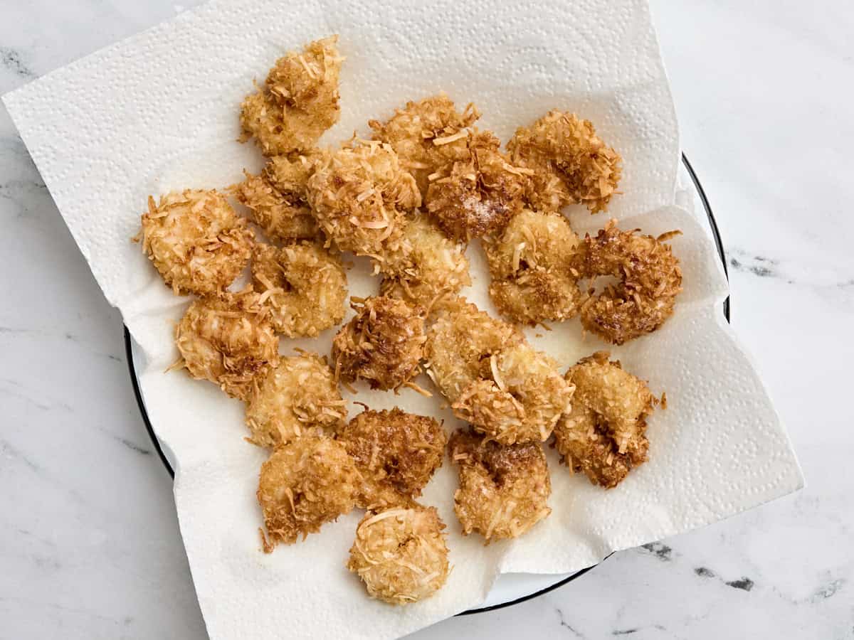 Freshly fried coconut shrimp on a paper towel.
