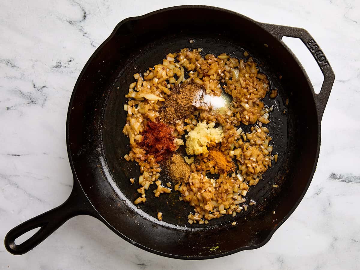 Butter chicken seasonings and pressed garlic in a skillet with satueed diced onion.