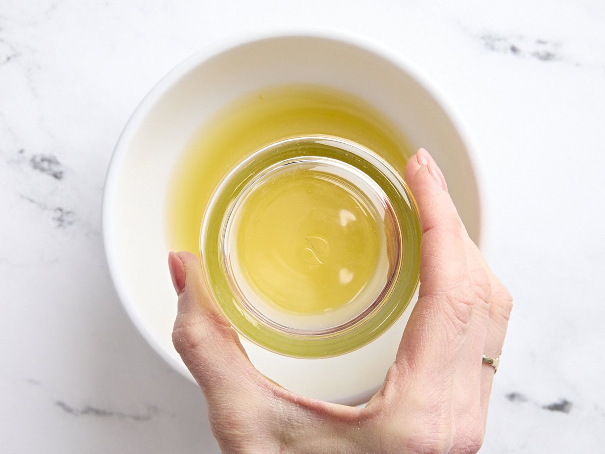 The rim of a rocks glass being pressed into some orange juice.