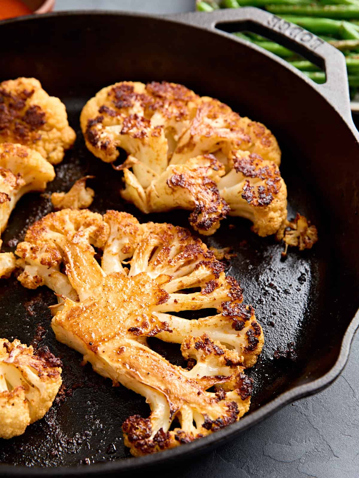 Side view of cauliflower steaks in a skillet.