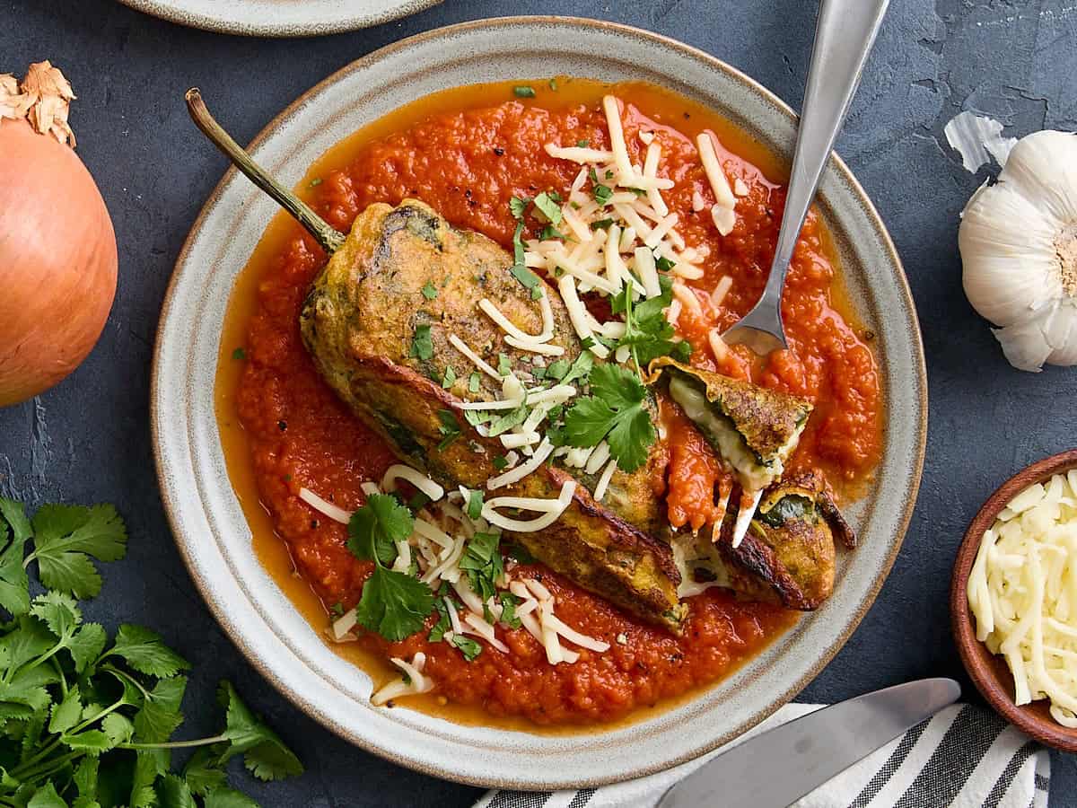 Overhead view of a chile relleno on a plate with a fork taking some.