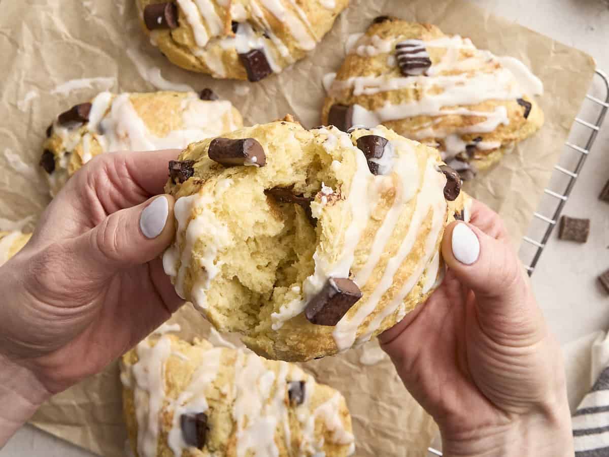 Hands breaking a sourdough chocolate chip scone in half.