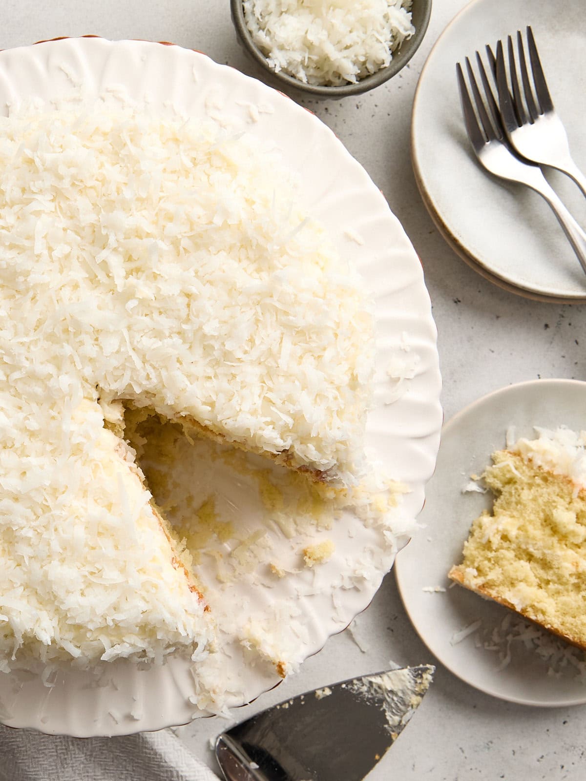 Overhead view of a coconut cake with a slice cut out.