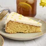 Side view of a cornbread cake, topped with honey buttercream frosting on a plate.