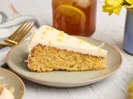 Side view of a cornbread cake, topped with honey buttercream frosting on a plate.