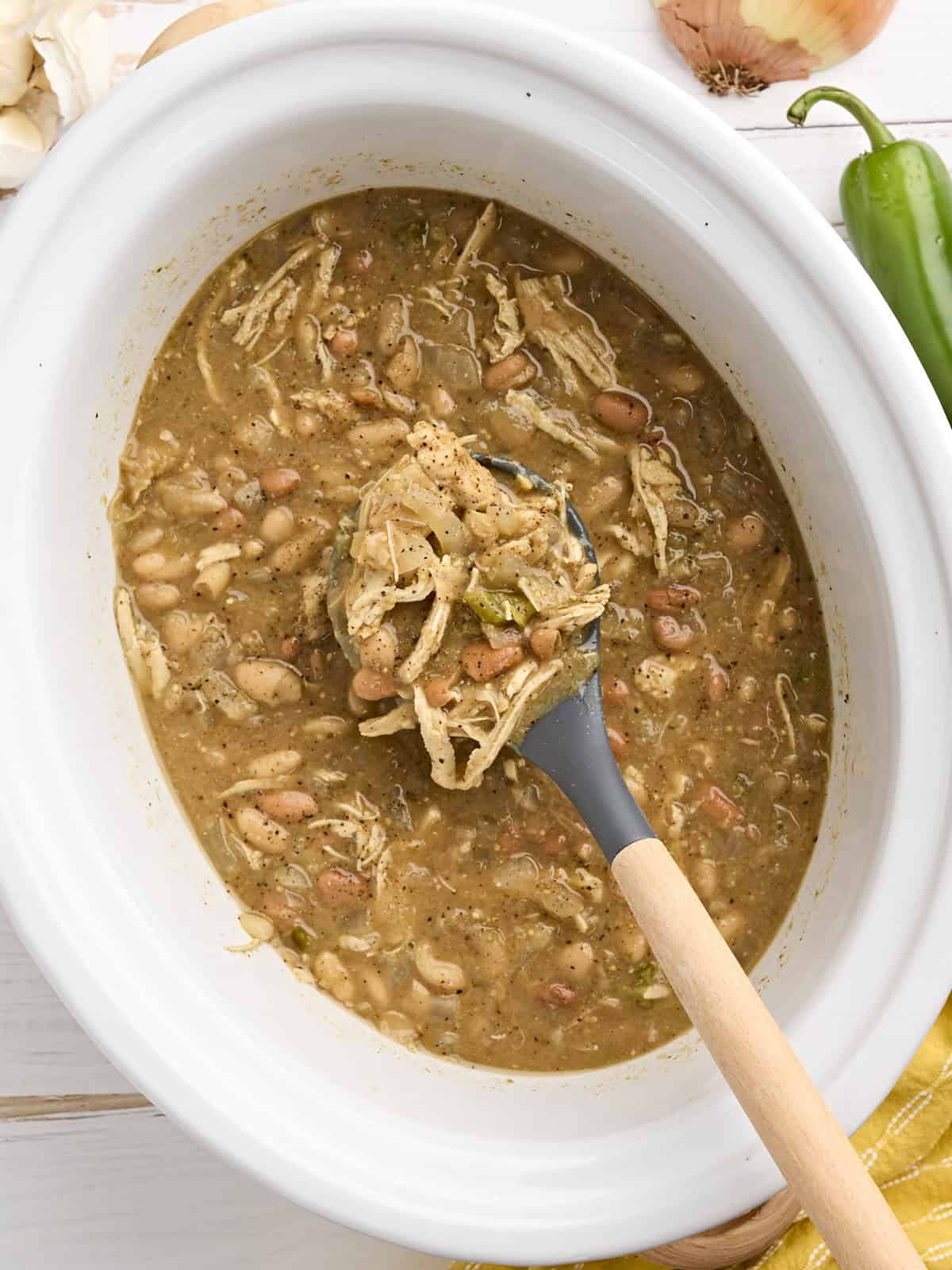 The slow cooker does all the work with this easy, flavorful, and healthy white chicken chili. This "dump and go" dinner will become a family favorite! BudgetBytes.com Overhead view of slow cooker white chicken chili in a crockpot.