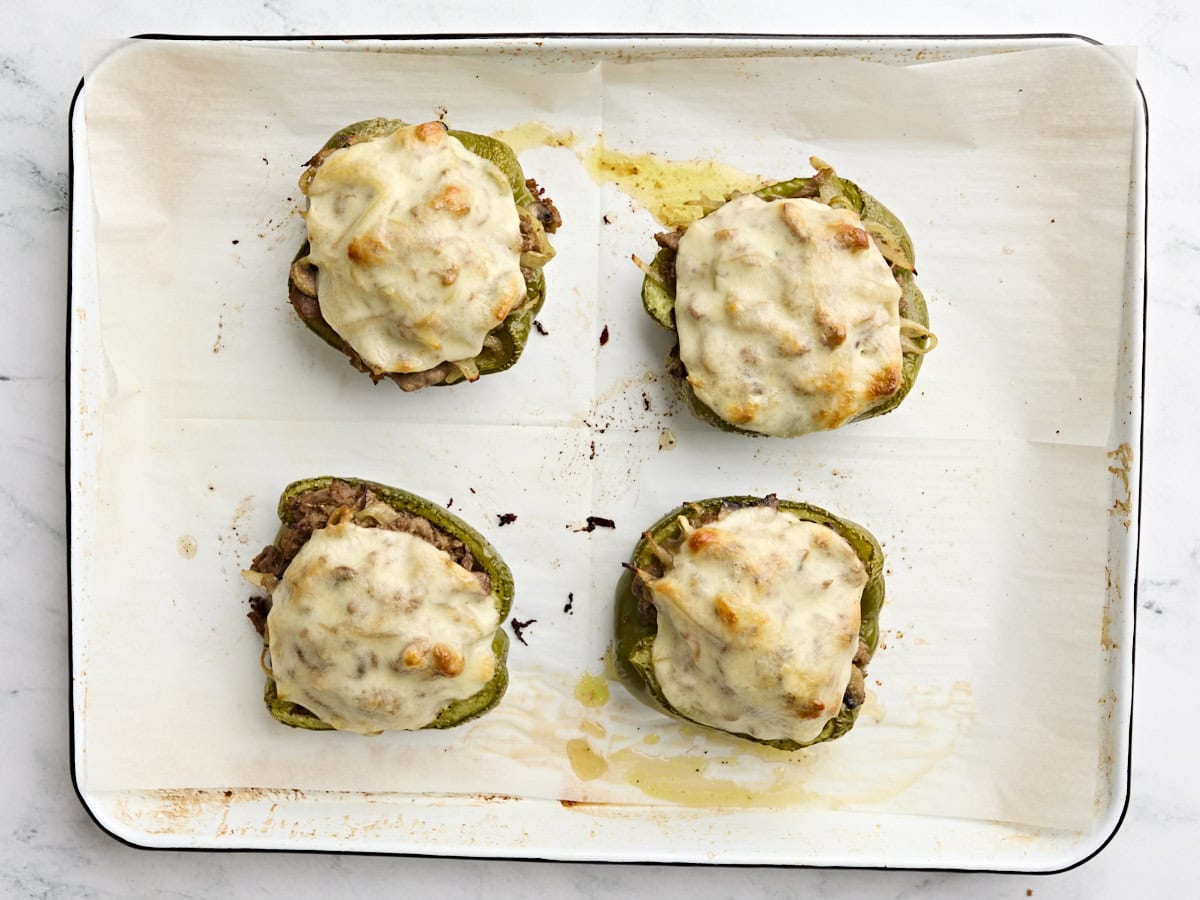 Finished philly cheesesteak stuffed peppers on a baking sheet.