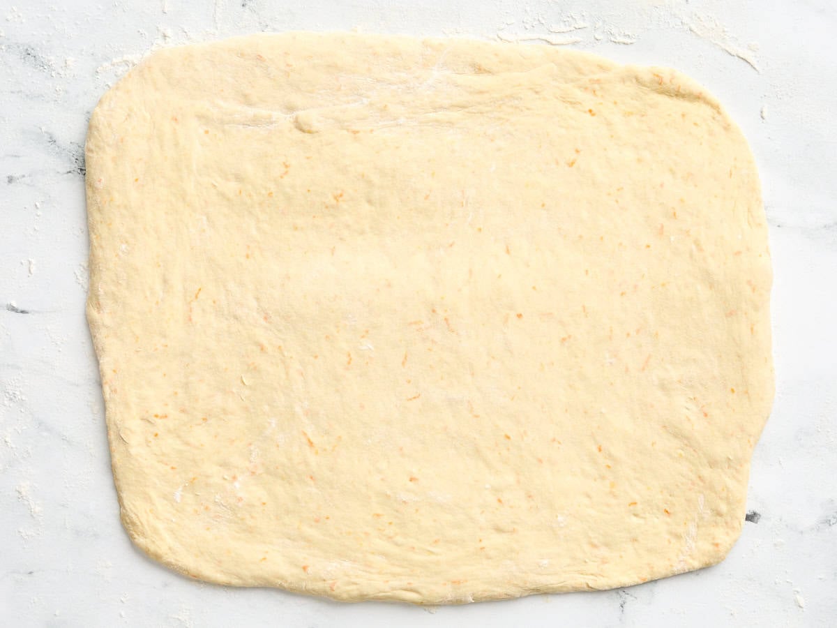 Orange roll dough rolled out into a rectangle.