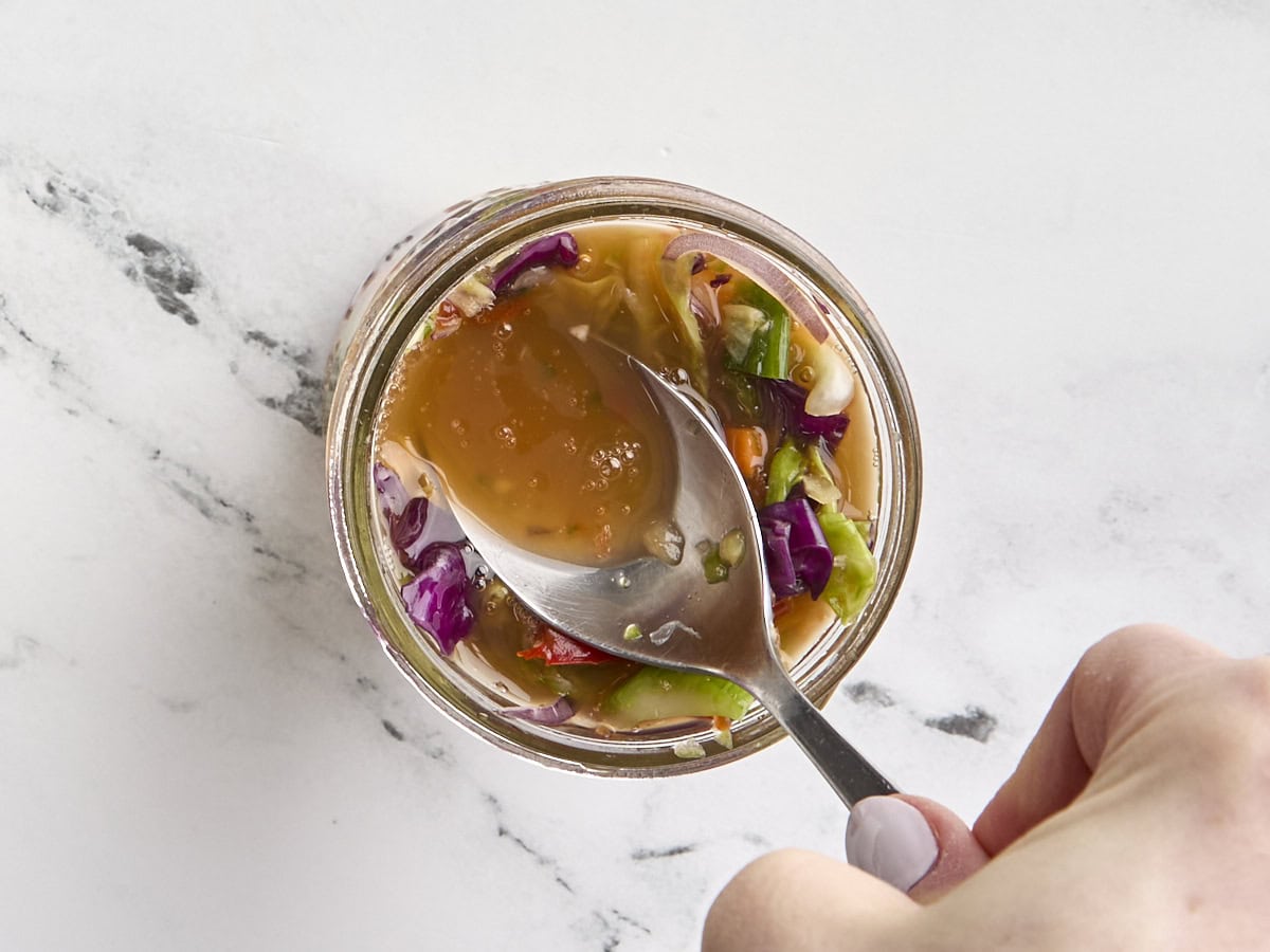 Extra vegetable brine being added to a jar of homemade fermented vegetables.