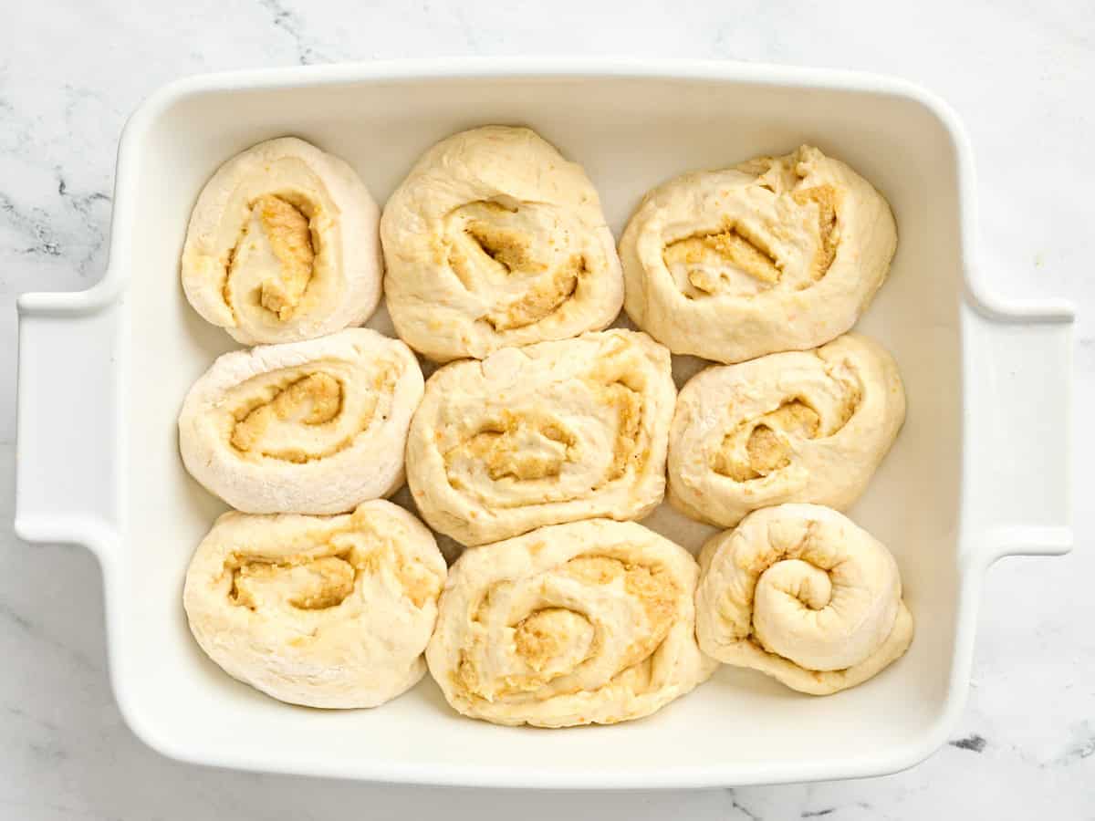Unbaked orange rolls in a baking dish.