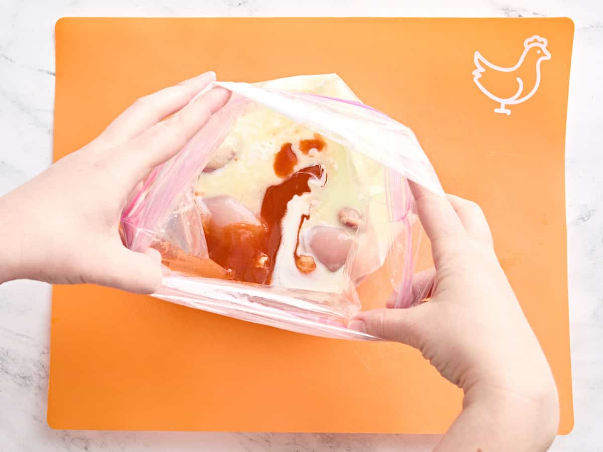 Buttermilk, hot sauce, pickle brine, and chicken thighs in a plastic bag.