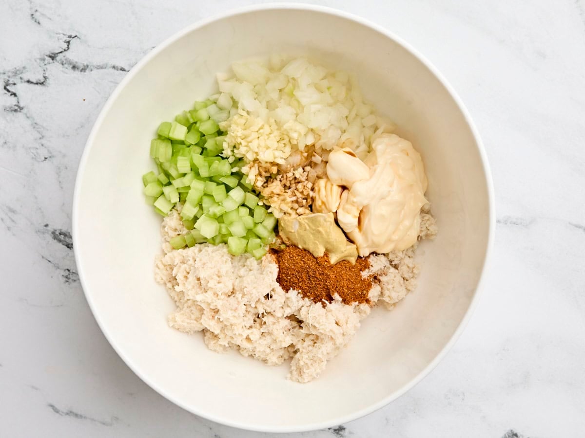 Diced onion, celery, garlic, seasonings mayonnaise, and canned crab meat in a mixing bowl.
